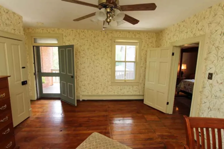 Empty room with hardwood floors, yellow wallpaper, and ceiling fan