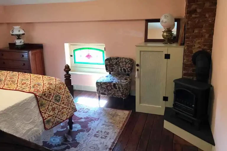 Attic bedroom with stained glass window and armchair.