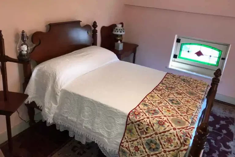 Bedroom with white linens and patterned bedspread.