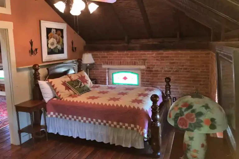 Attic bedroom with exposed brick wall and stained glass window.