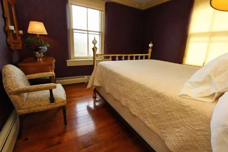 Cozy bedroom with a large bed, wooden floor, and a window with natural light.