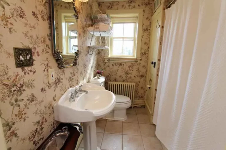 A small bathroom with floral wallpaper.