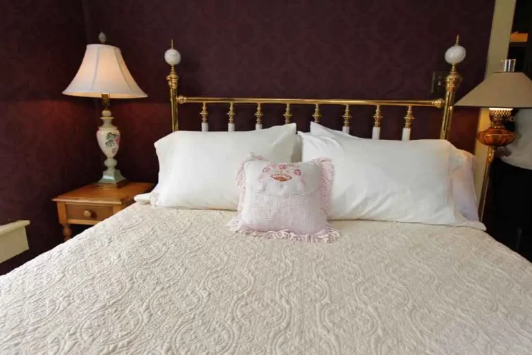 Elegant bed with white bedding and a decorative pillow against a burgundy wall.